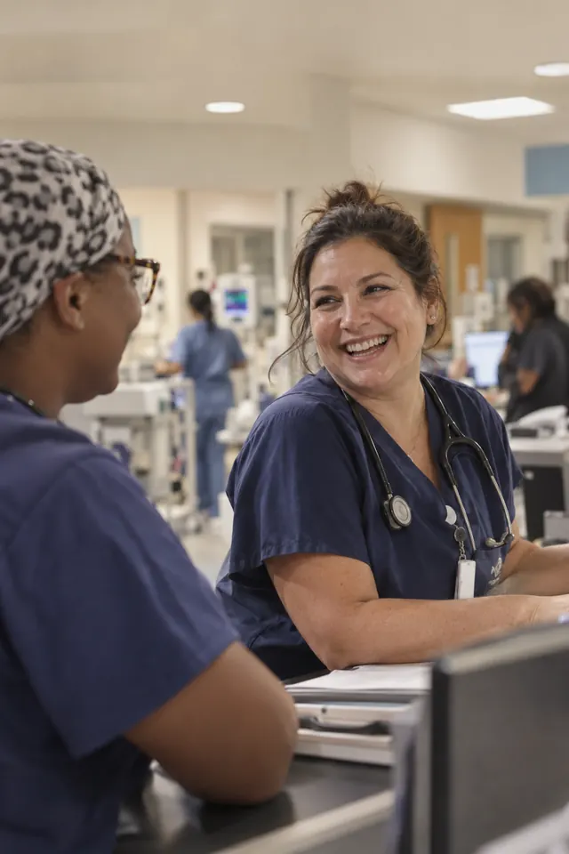 A nurse laughing with a coworker during a shift